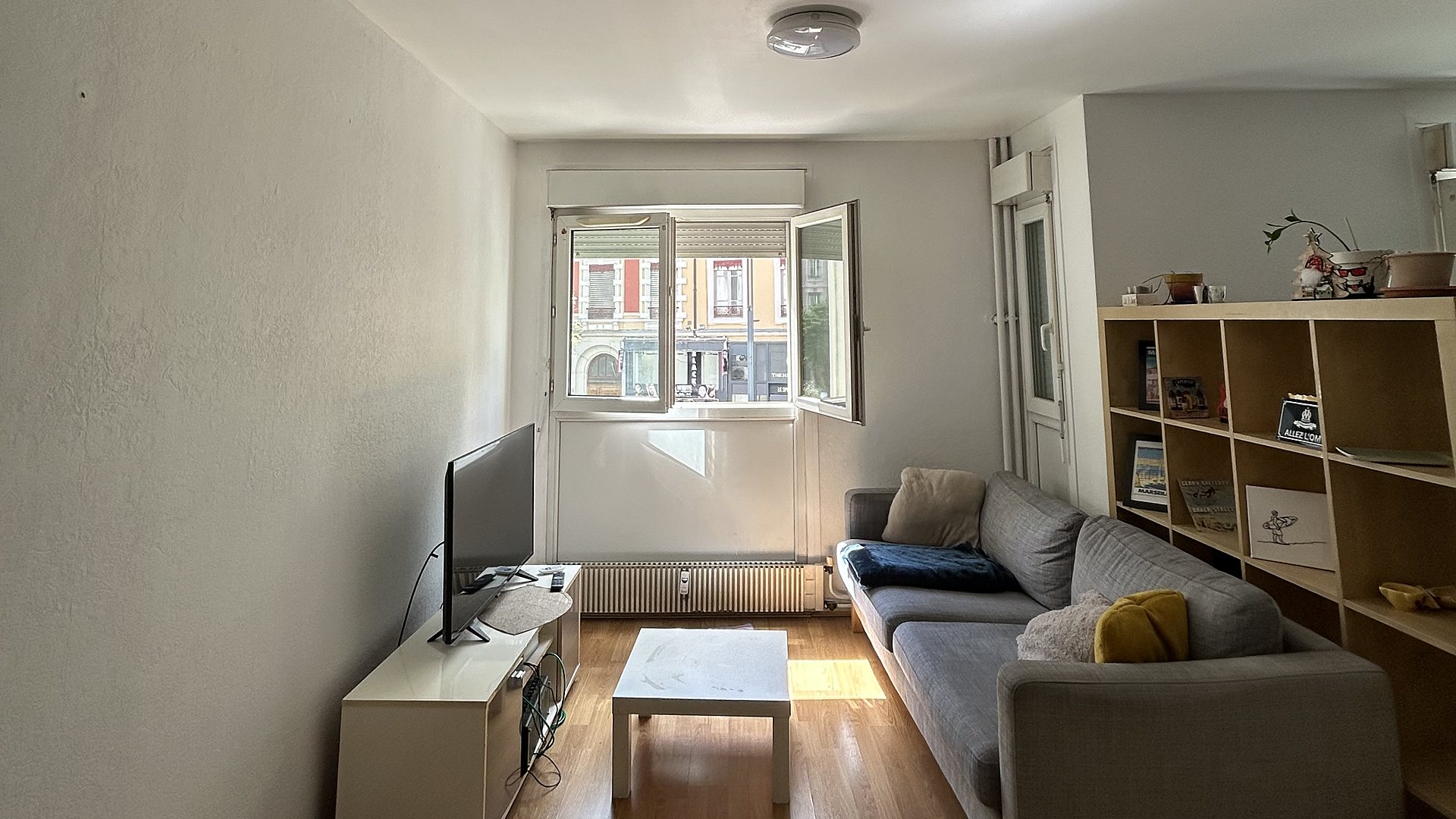 Salon scandinave à Lyon : canapé gris, grande bibliothèque en bois, meuble TV et table basse blancs