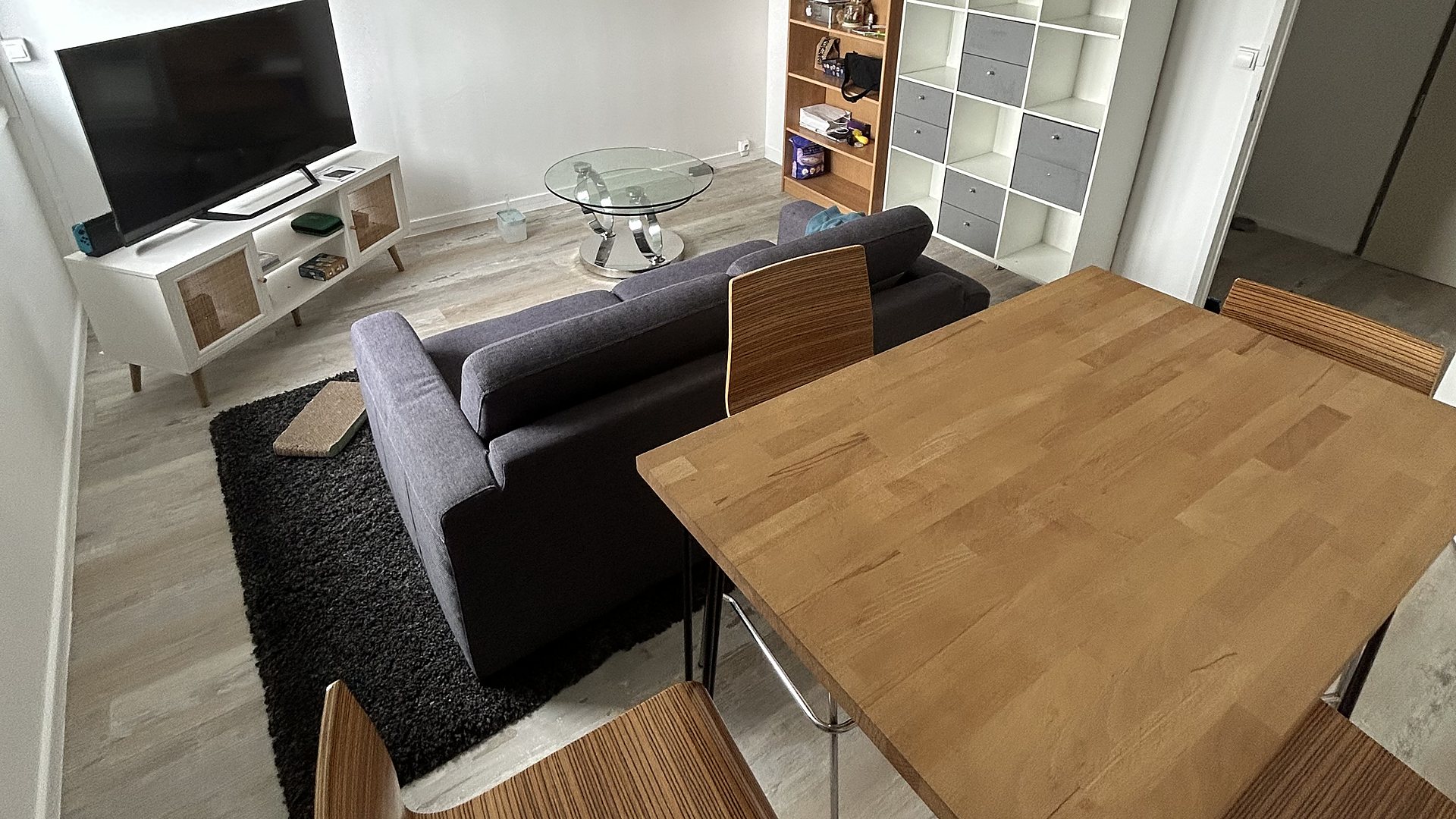Séjour vintage à Lyon : table en bois massif, chaises rétro, canapé gris et table basse en verre